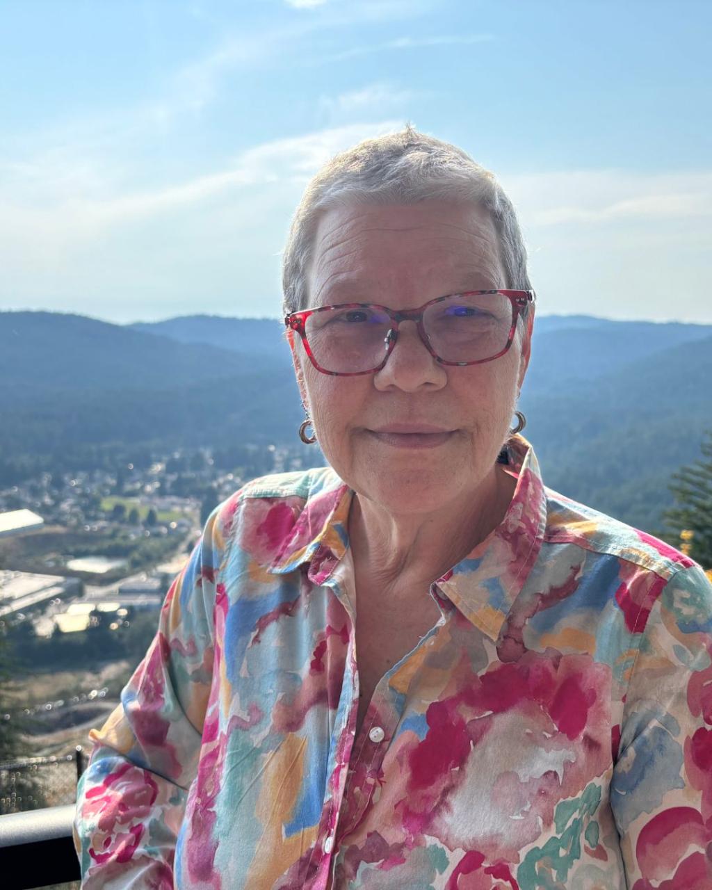 Frances Jorgensen smiling on a balcony overlooking a valley.