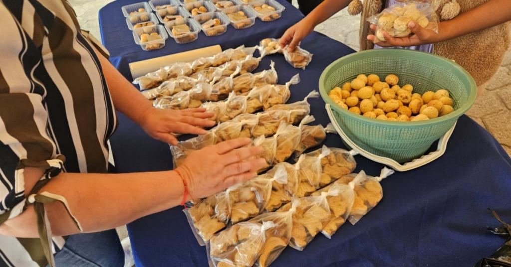 Takeaway containers of food products laid out on a table, with two people stacking items into piles.