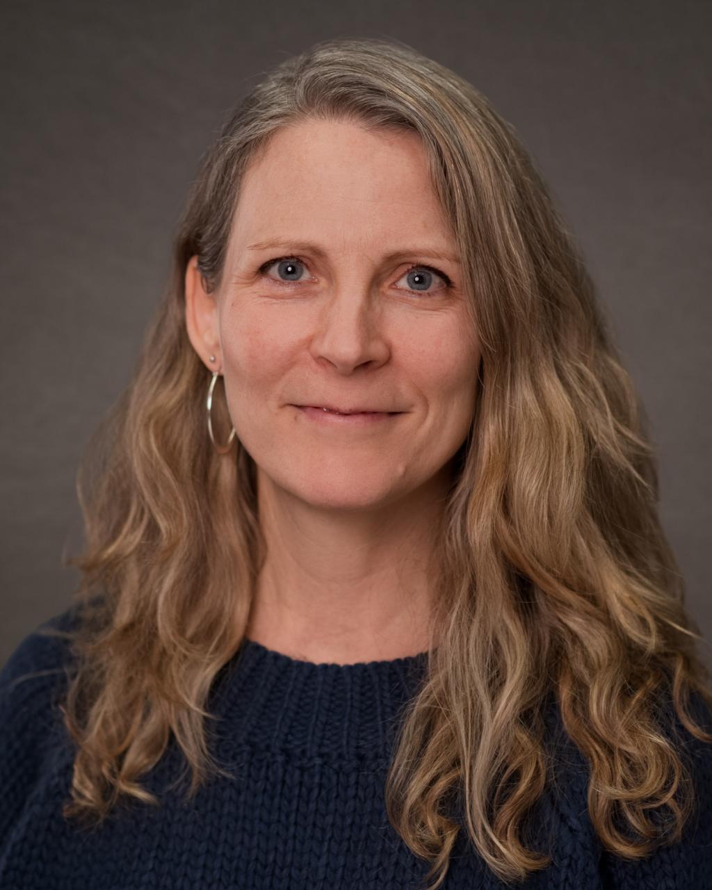 woman with shoulder length wavy blonde hair wearing a black sweater