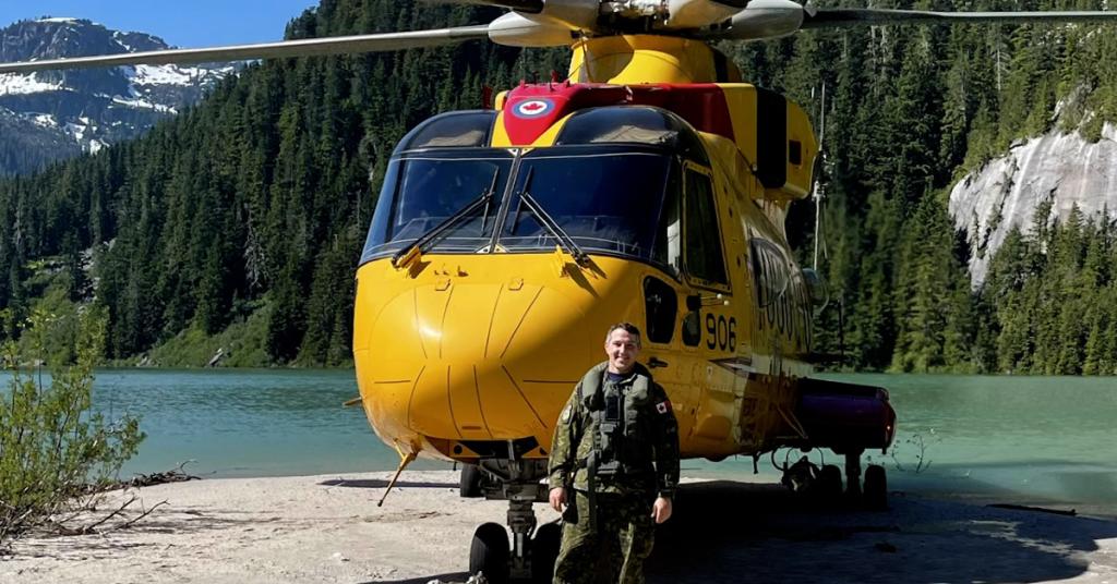 Steven Smith standing in front of a yellow Canadian military helicopter 