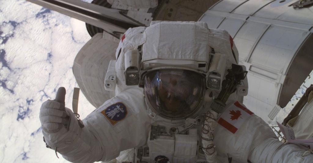 Chris Hadfield in astronaut gear on a space walk with Earth and the space shuttle in the background