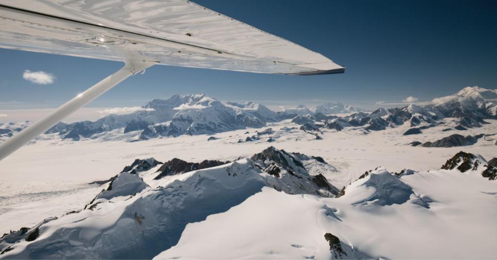 Wing of a small plane over snowy mountains