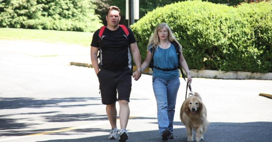 Two people walking with a service dog