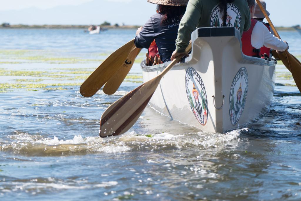 A group of people paddle a canoe through the water. 