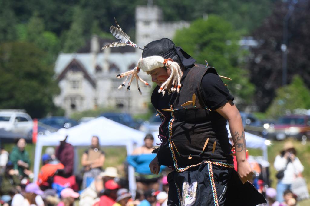A Lekwungen dancer performs with Hatley Castle in the background
