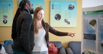 A student points to a display while another student looks on.