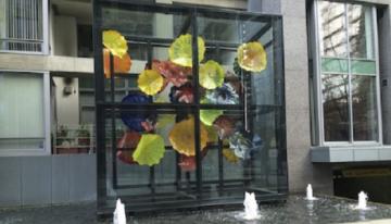 An art display over a fountain that has many coloured pieces cut out that resemble flowers.