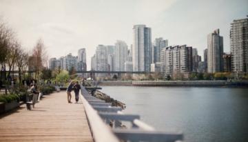 people along a boardwalk on the waterfront in a city.