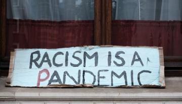 Hand made sign with the words "cacism is a pandemic" printed on it.