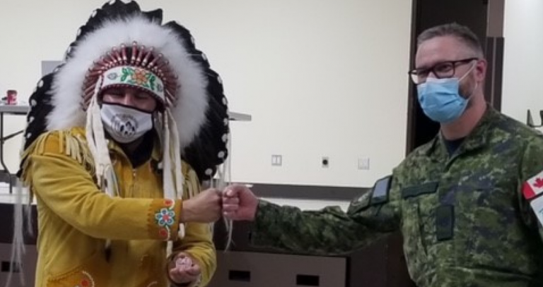Tim Stackhouse in CAF fatigues pounds fists with Onekanew (Chief) Sinclair.