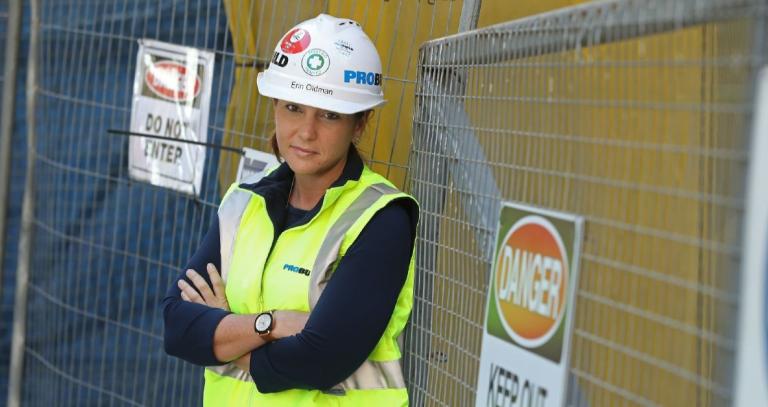 Erin Oldman standing with her arms crossed in a construction uniform