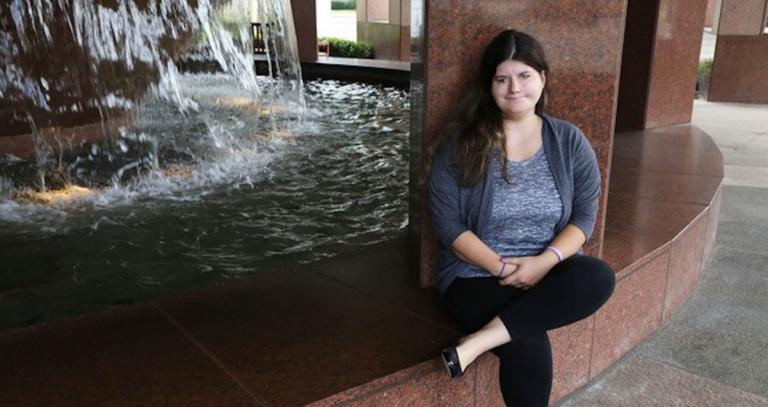 Student Kelsey Ferrill sitting in front of a fountain.