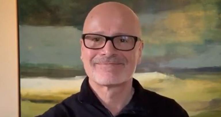 President Steenkamp stands with his back to a painting indoors