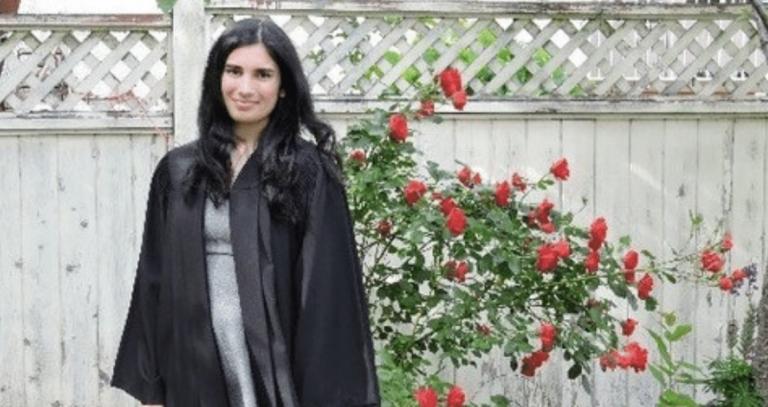 Serena Bains stands outdoors in graduation robe