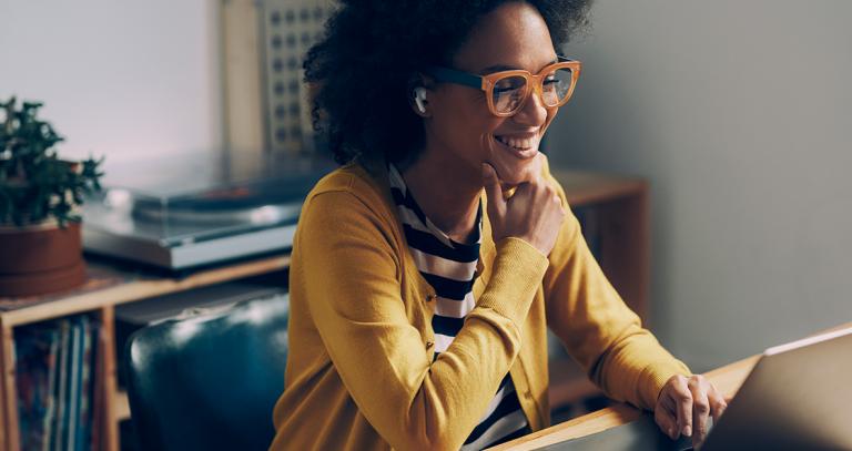 Smiling student sits in home office while on a video conference.