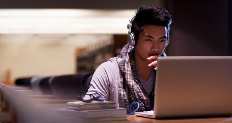 A student uses a laptop in a library.