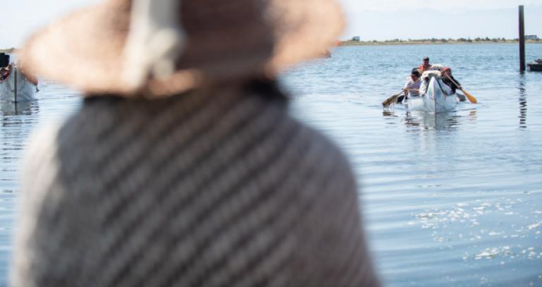 An Indigenous person waits onshore at Esquimalt Lagoon as a canoe arrives to ask for permission to land in a canoe protocol.