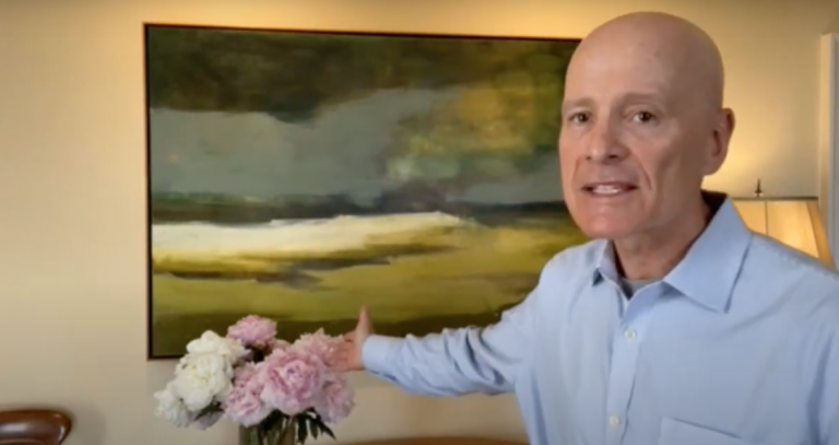 President Philip Steenkamp in his office gesturing to a big bouquet of peonies.