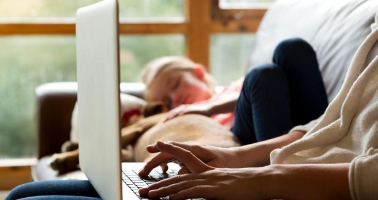 lady on laptop with child sleeping on couch