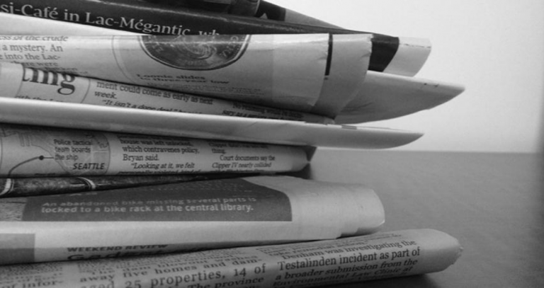 Pile of newspapers on a desk.