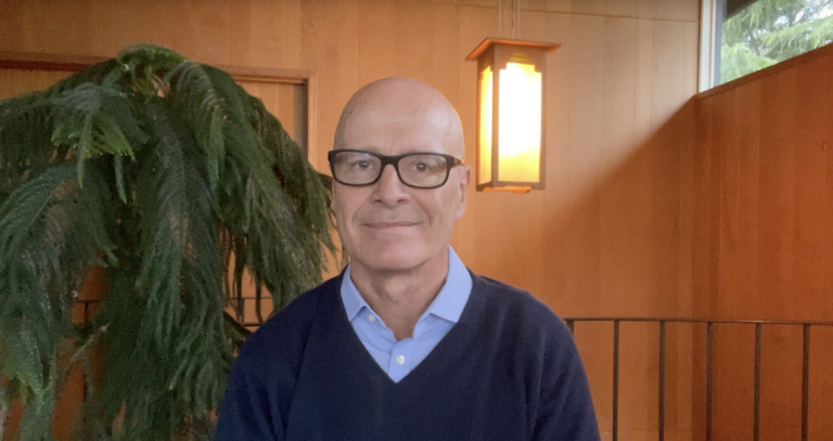 President Philip Steenkamp in his home with a big plant behind him and light pouring in from the window.