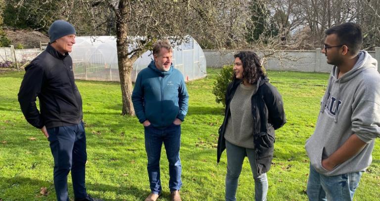 President Philip Steenkamp stands in the gardens talking to BBA in Innovation and Sustainability faculty and students.