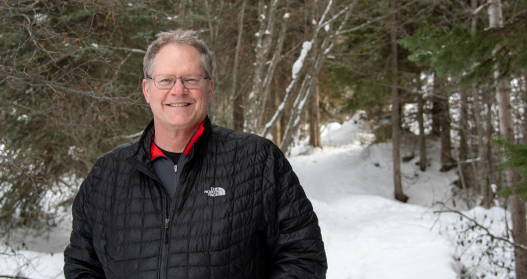 Dr. Graham Dodd head shot standing outside in the winter with the snowy forest behind