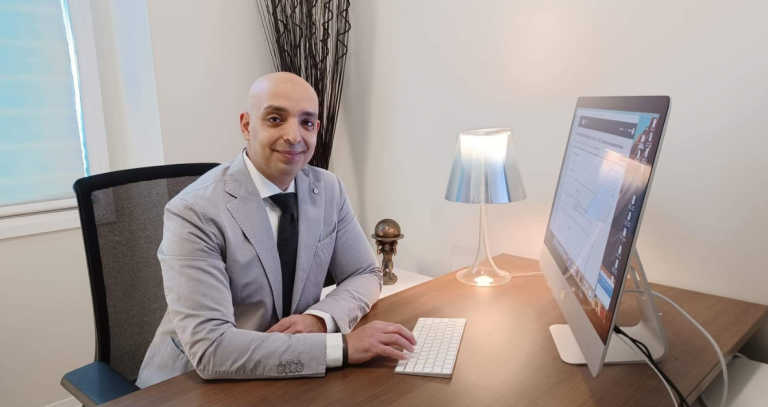 a man sits with his fingers on his computer keyboard at a desk.