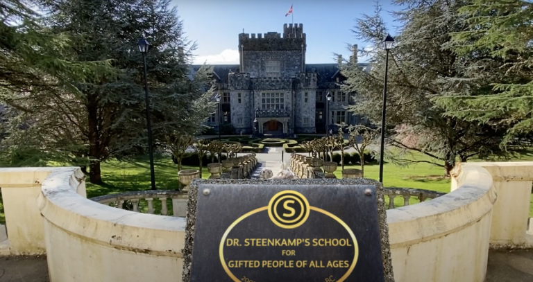 A stone sign in front of Hatley Castle reads "Dr. Steenkamp's School for Gifted People of All Ages" in gold lettering.