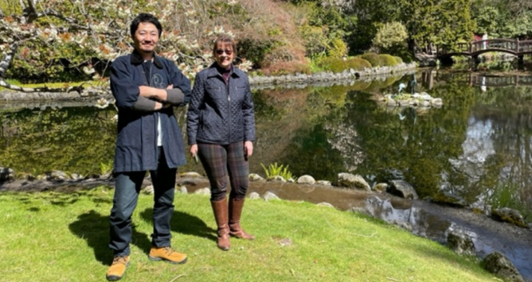 (Right) Hayato Ogawa of Ogawa Landscape designs designer for the RRU Japanese Garden; (left) Vera Gammert, Capital Project Manager Operations & Resilience  at  Royal Roads University standing in front of Japanese garden with pond in background.