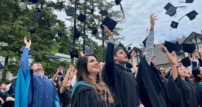 President Steenkamp and grads celebrate by throwing mortarboards into the air at Spring Convocation 2022.