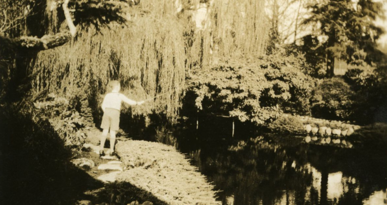 An old black and white picture of a boy fishing from the island in Royal Roads' Japanese Garden in Hatley Park