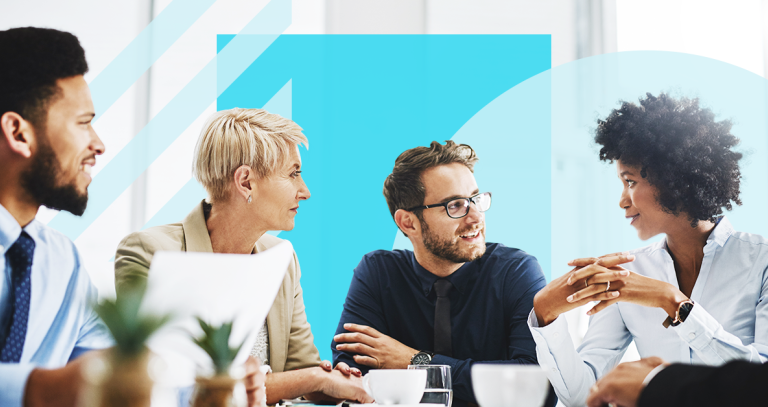 Four people sitting at a table talking with a blue-coloured background.