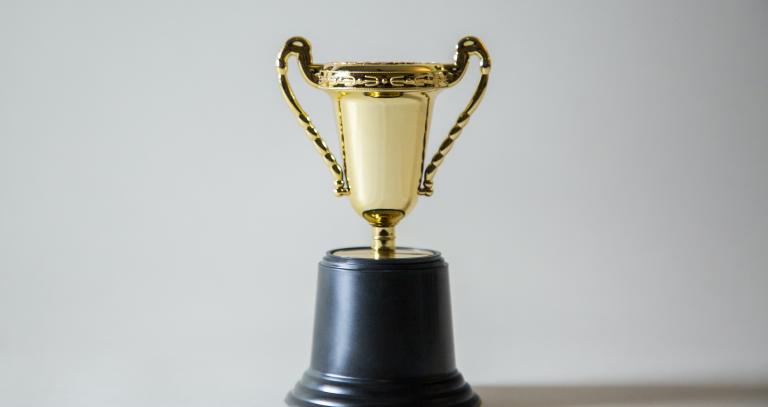 A gold trophy with a black base in front of a white background.