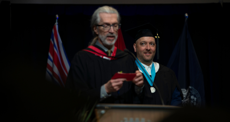 A graduate wears a medal while on the convocation stage.