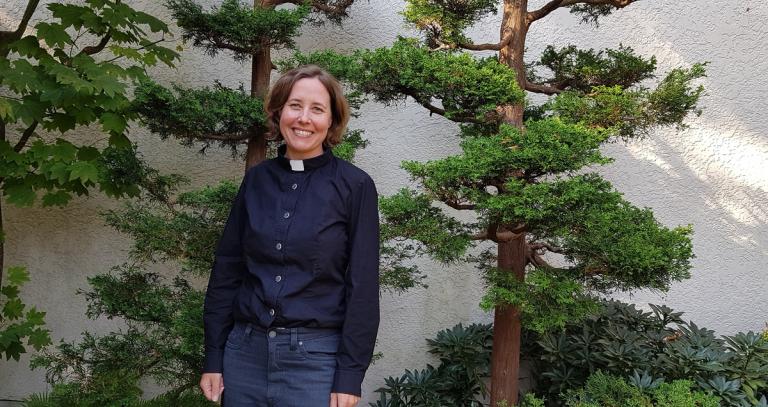 MBA grad Alecia Greenfield stands in front of some trees.