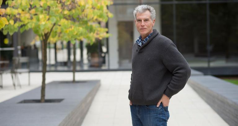Thomas Homer-Dixon stands in front of a modern building with hands in pockets