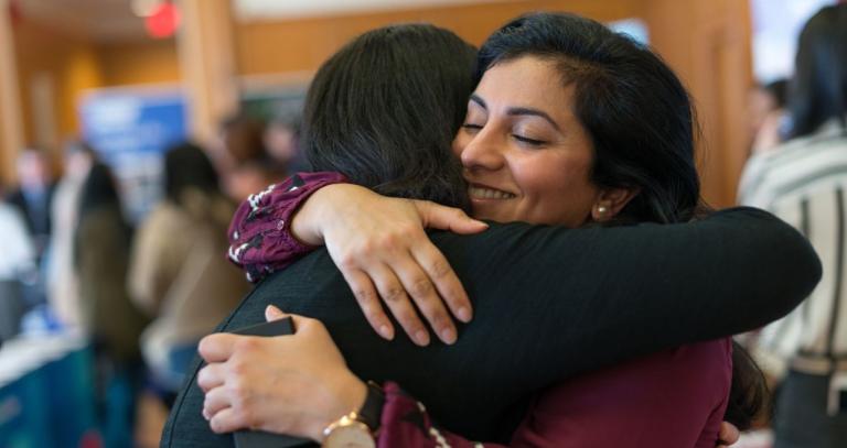 A student hugs a supporter in celebration in a crowded room