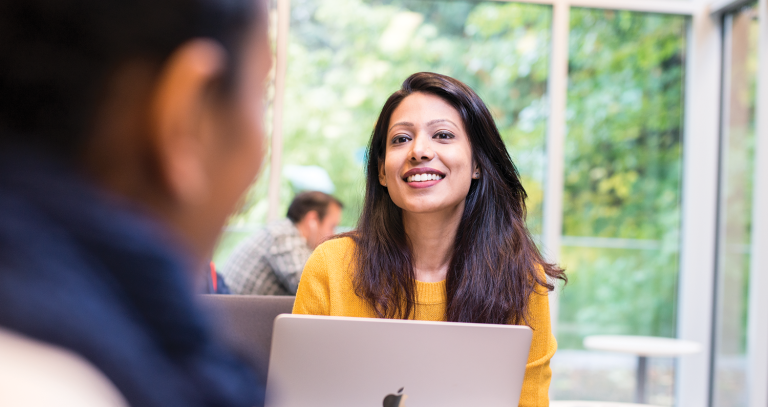 student smiling with their laptop