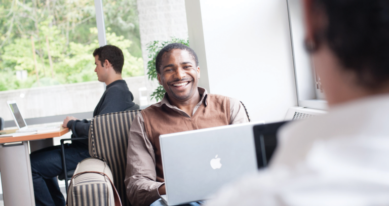 student using laptop while smiling