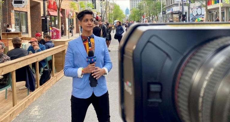 Iman Kassam stands in downtown Montreal in front of a camera, holding a CTV microphone.