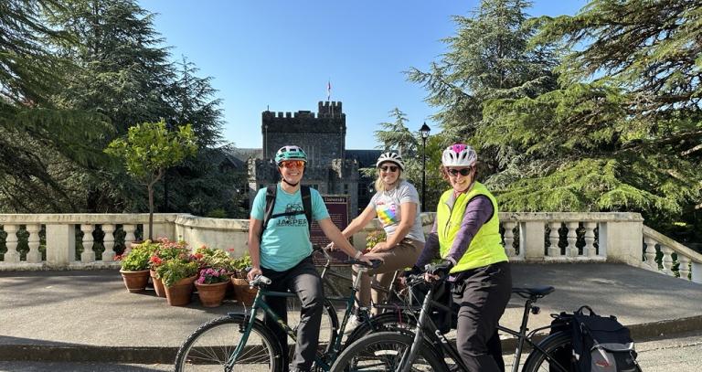 Three people on bicycles in front of Hatley Castle.