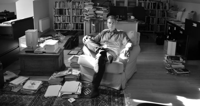 A black and white photo of a man sitting in his office.