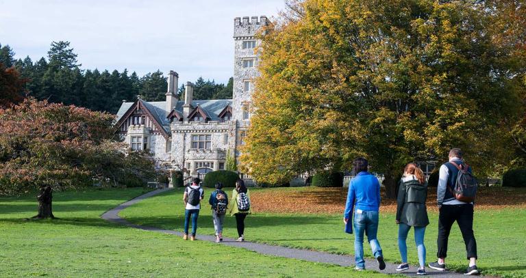 A group of students walk along a path toward Royal Roads University