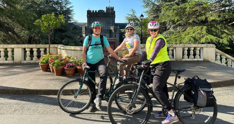 Three cyclists posing in front of Hatley Castle.