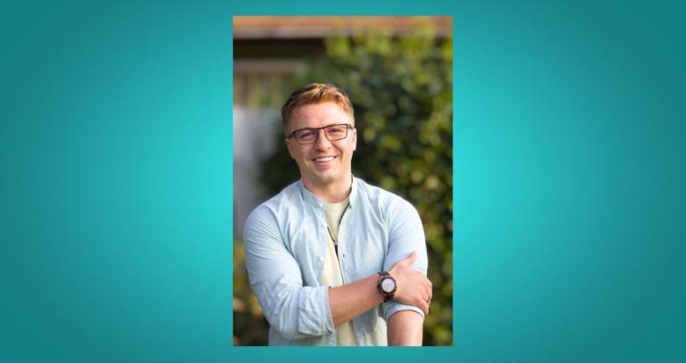 Liam Moise smiling with a tree behind him.