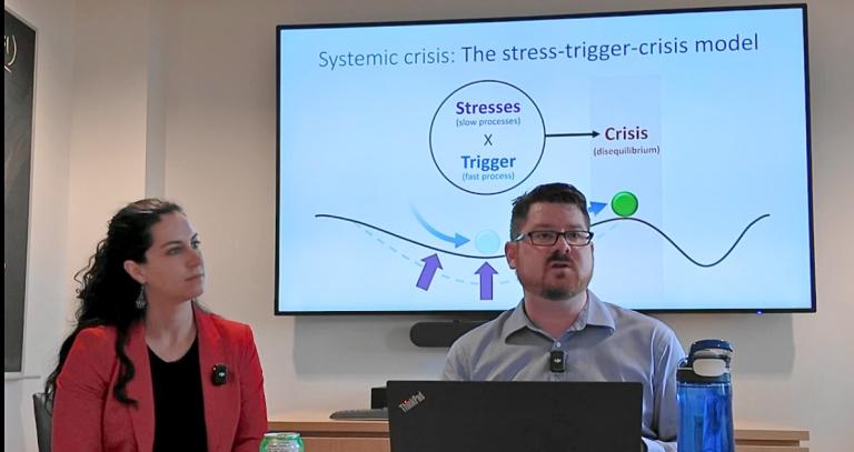 Megan Shipman and Michael Lawrence seated in front of a large presentation screen.
