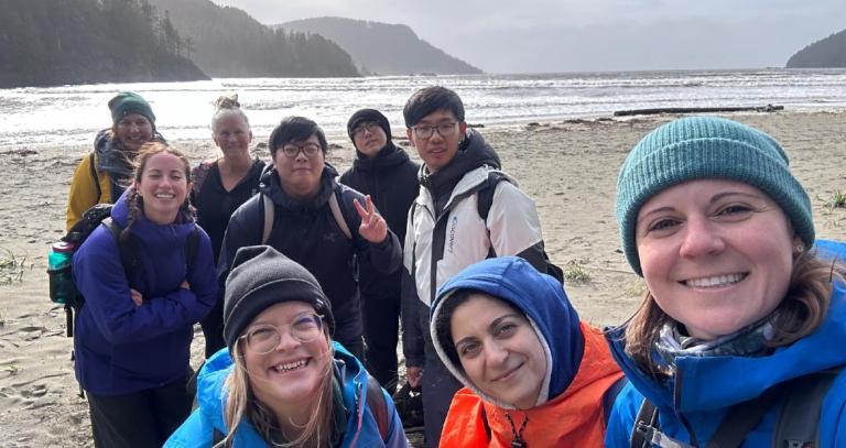 Group of smiling students on a West Coast beach taking a selfie.