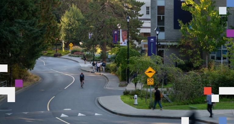 A bike winds down a paved hill surrounded by lush trees at Royal Roads University