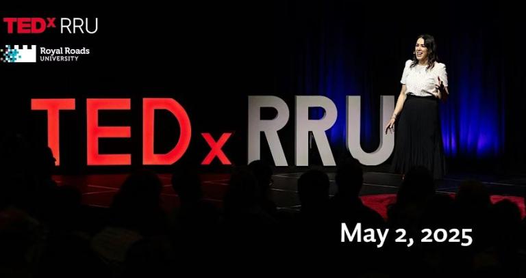 A presenter stands on the TEDxRRU stage, beaming her story into the darkness. 